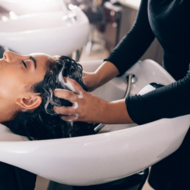 hairdresser washing a customer's hair at a sink - reputation management for personal services