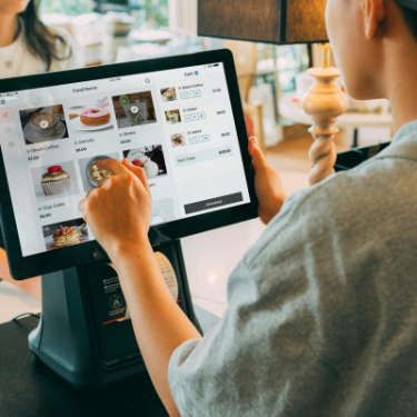 store clerk at cash register using review management for retail